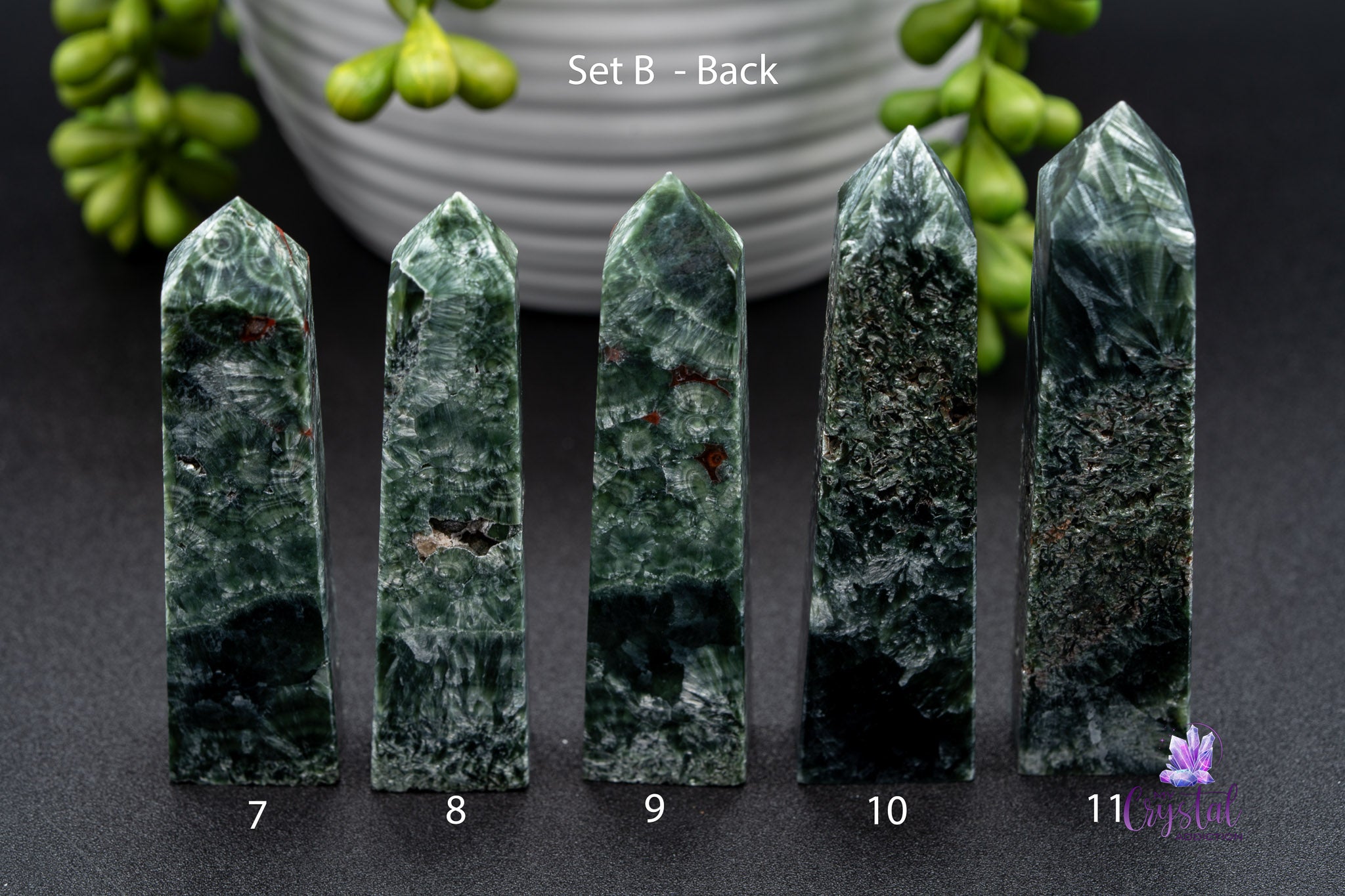 Set of five polished green crystal towers, labeled 7 to 11, on black surface with plant decor