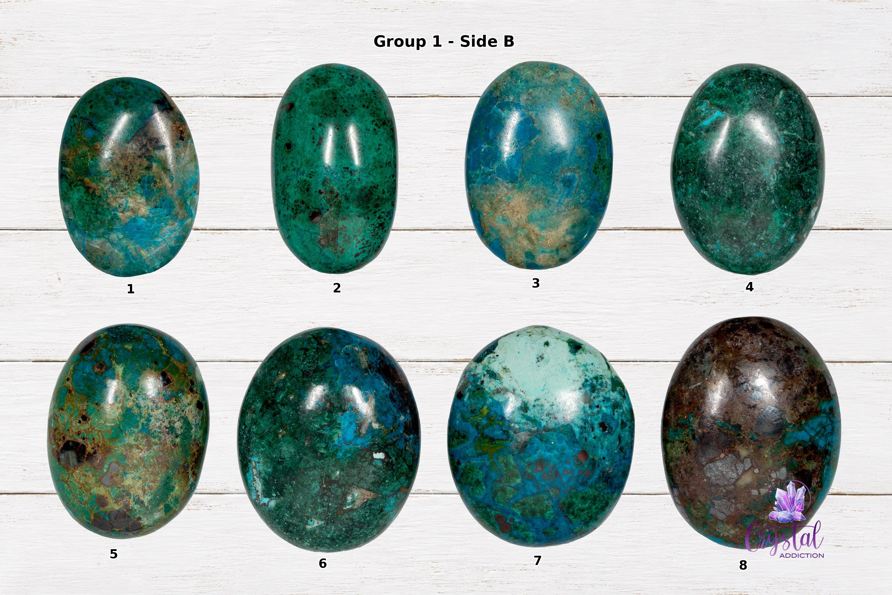 Back sides of chrysocolla palm stones numbered 1 through 8 on a white wood background.