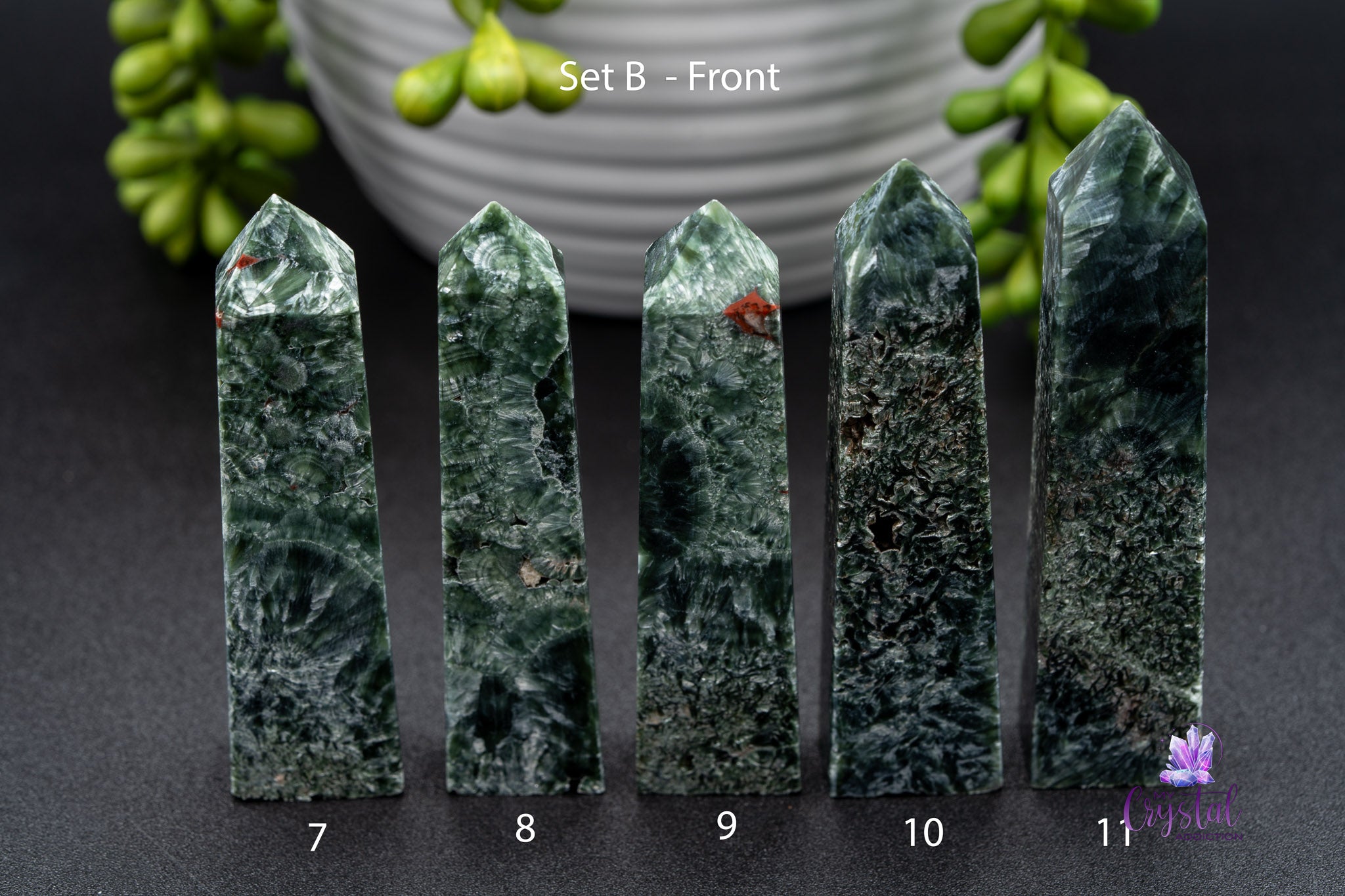 Set of five polished green kambaba jasper crystal towers labeled 7-11 on black surface