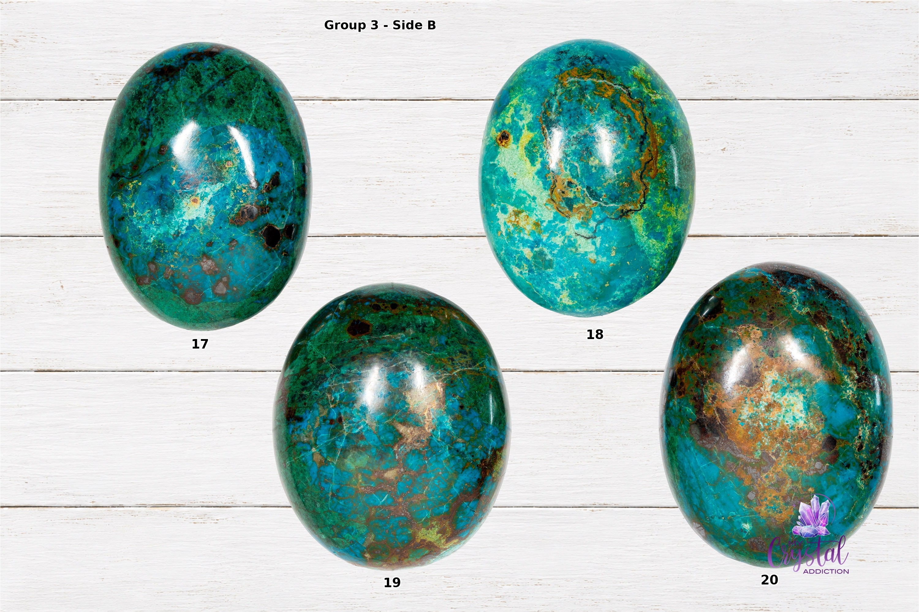 Back sides of chrysocolla palm stones numbered 17 through 20 on a white wood background.