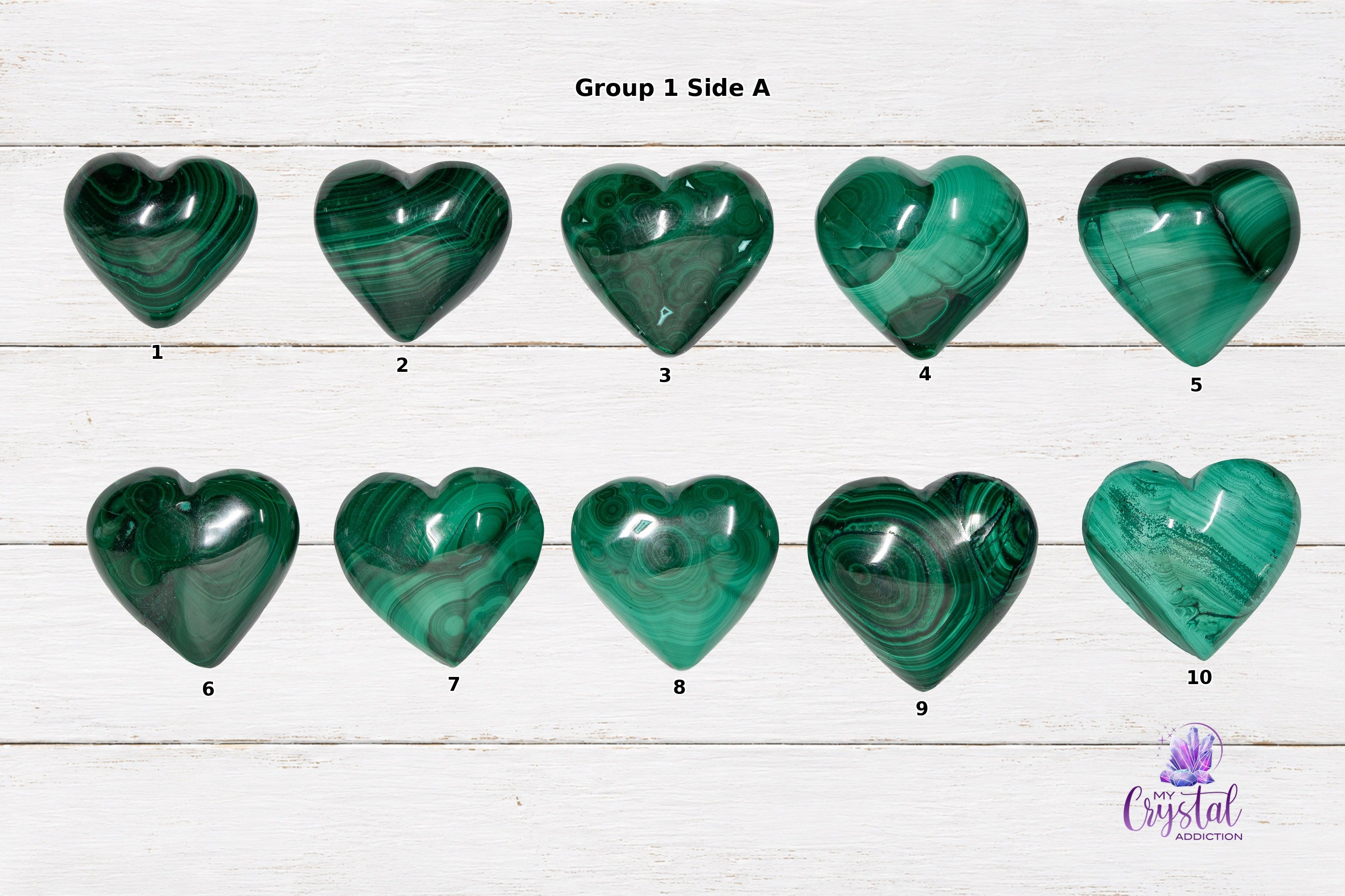 Front views of polished malachite heart carvings with green bands and circular patterns on white wood.