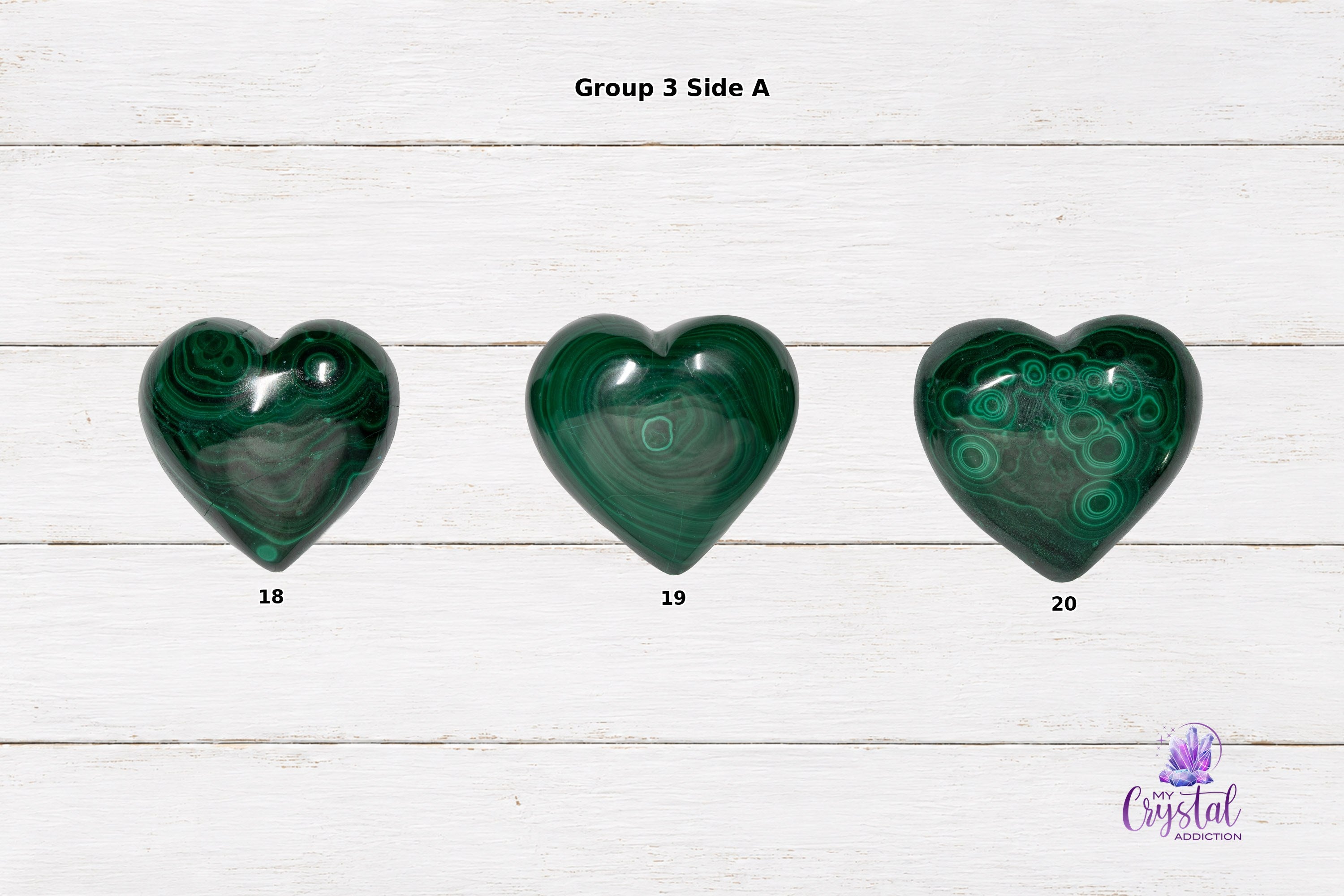 Front views of polished malachite heart carvings with circular eye-like patterns and green bands.