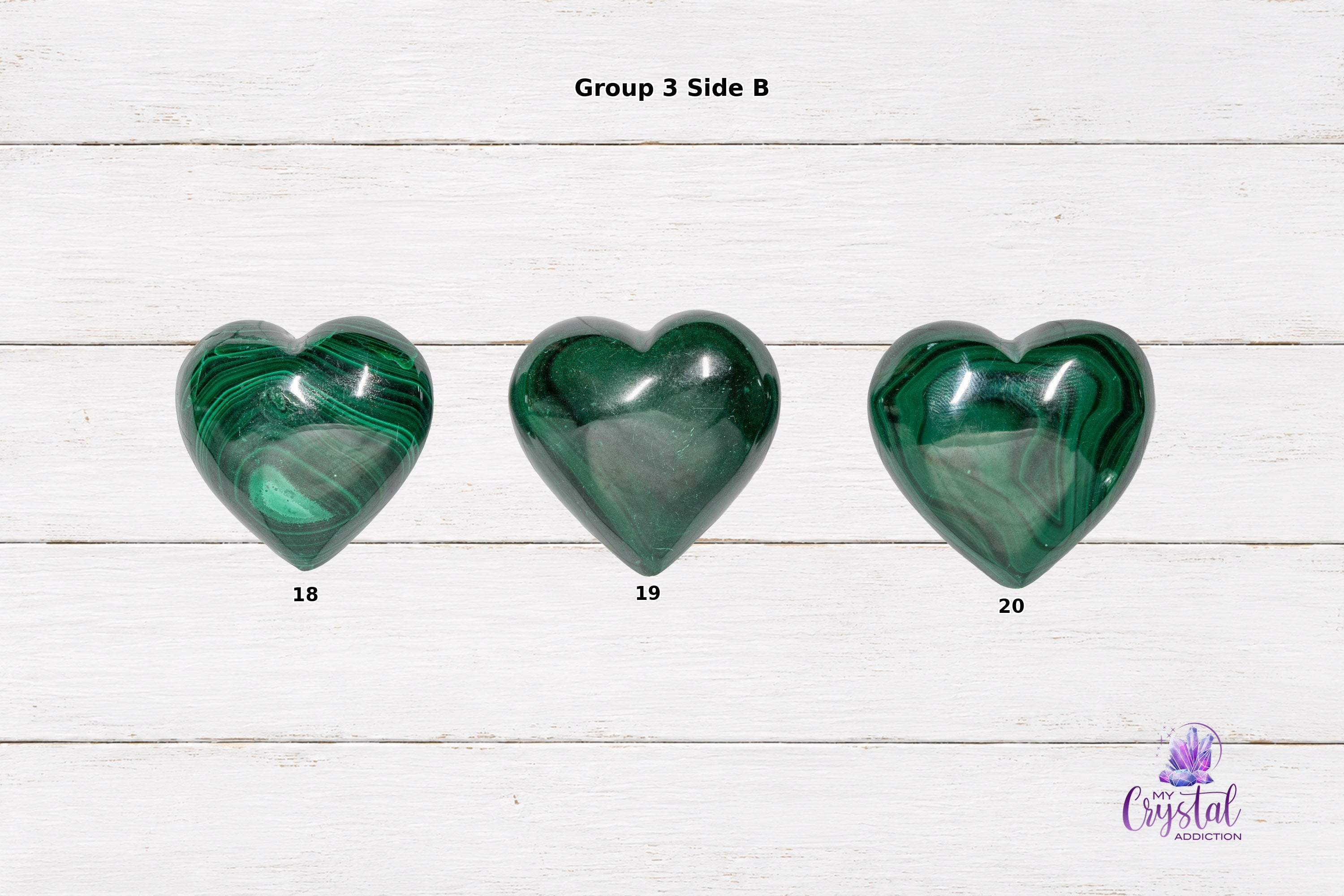 Alternate-side views of polished malachite heart carvings with glossy green banding on white wood.