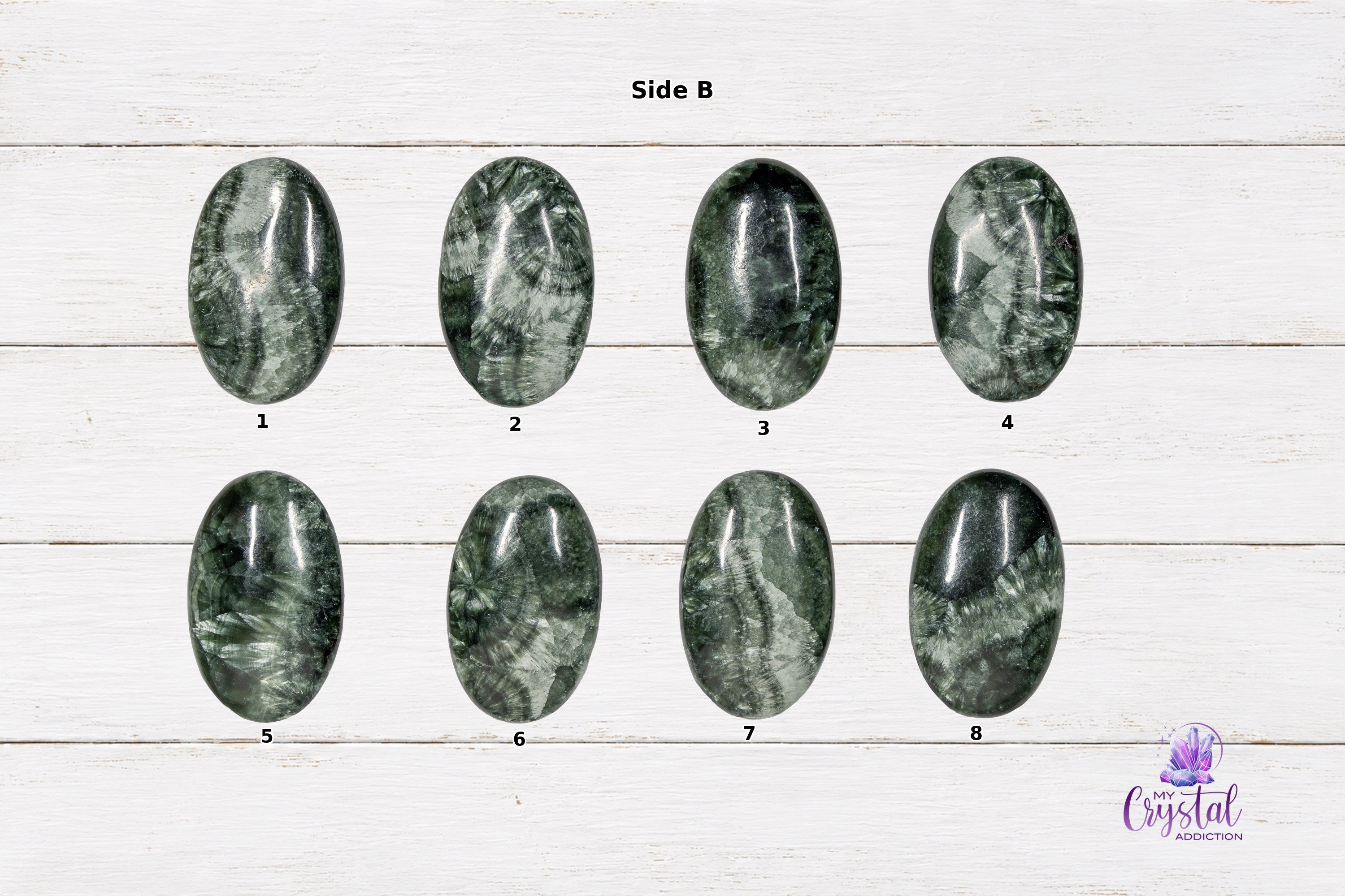 Side B view of numbered polished Seraphinite mini palm stones on a white wood background.